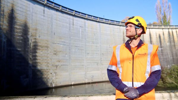 Man in PPE with hydro dam in background