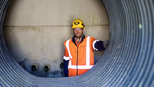 Man in PPE with interior of corrugated pipe in foreground