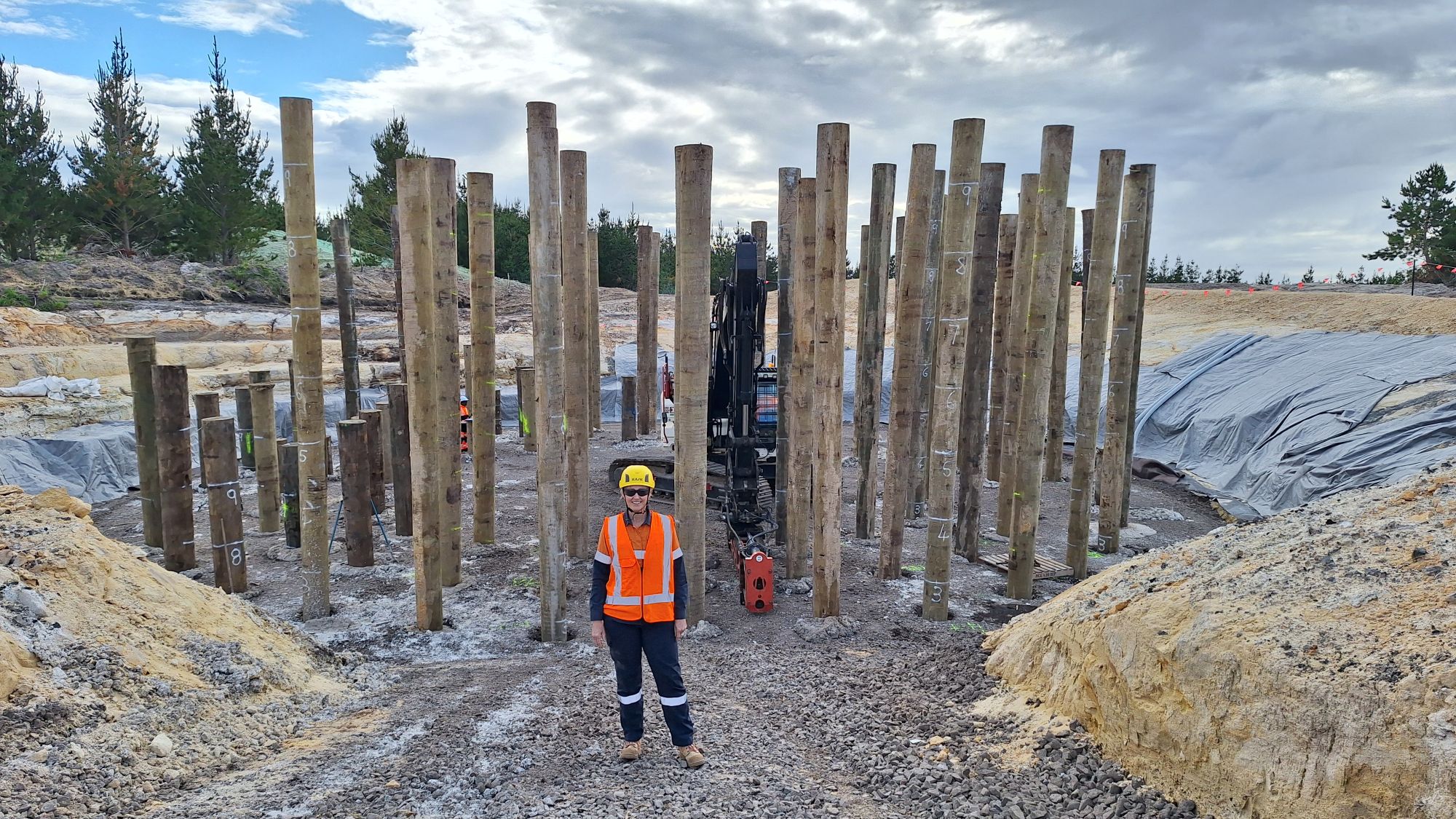 Person stood in front of a circle of wooden poles on a construction site