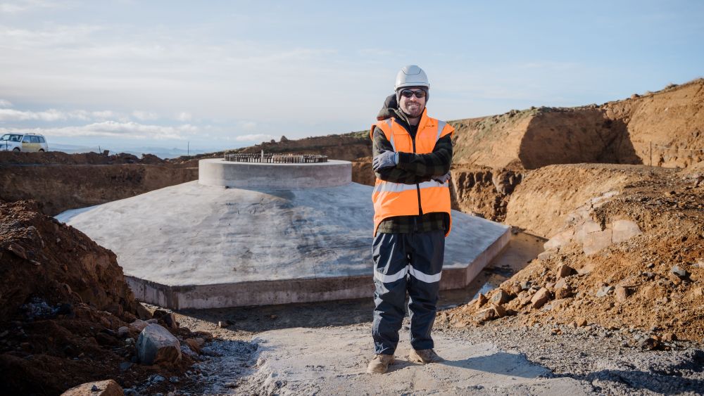 Stewart Reid stood in PPE next to the construction of a wind turbine tower base