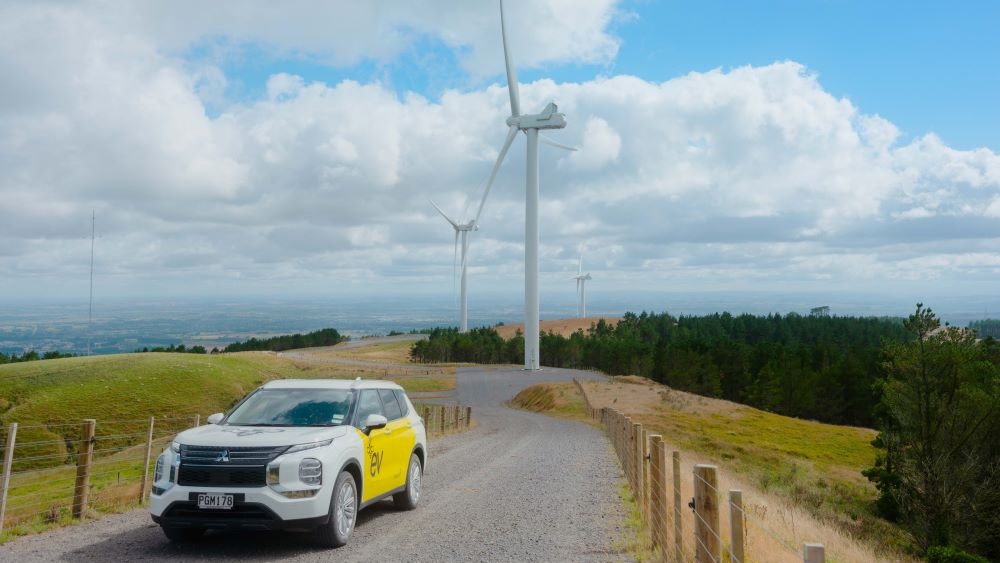 Mercury branded vehicle on road with wind turbines in background